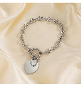 Détail de pendentifs cœur en argent avec zircons et fermoir OT sur fond de soie