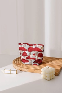 Detail of mushroom pattern fabric makeup bag with heart zipper and brand logo tag