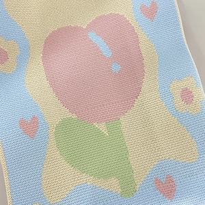 Close-up of vibrant knitted fabric featuring heart and tulip jacquard patterns