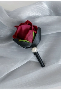 Detail of burgundy satin rose boutonniere with pearl and crystal stem on silk fabric