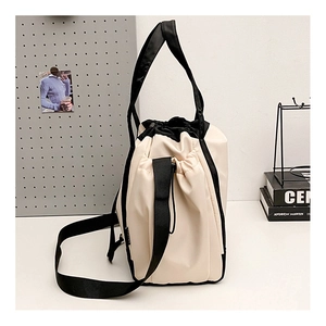 Close-up of cream white drawstring shoulder bag with black strap and star logo detail