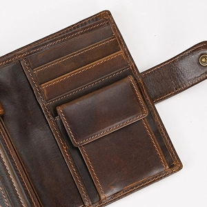 Macro detail of dark brown leather wallet showing card slots and snap coin pocket
