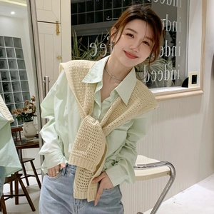 Detailed close-up of a beige hollow knit shawl with DD Logo embroidery on a green shirt