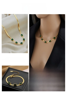 Detail of emerald green crystal stone pendants on a golden snake chain necklace and bracelet