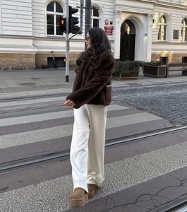 Street style view of short brown faux fur coat paired with wide-leg pants and platform boots