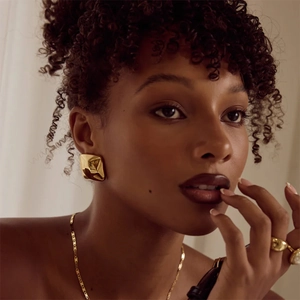 Polished 18k gold-plated textured square stud earrings on a model with warm lighting