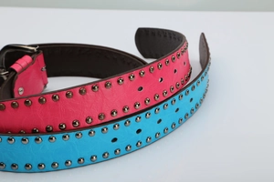 Detail of pink and blue punk rivet belts with metal studs and single-prong buckle