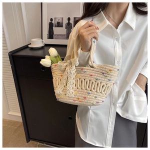 Detail of cream straw bucket bag featuring a white lace bow and colorful polka dots