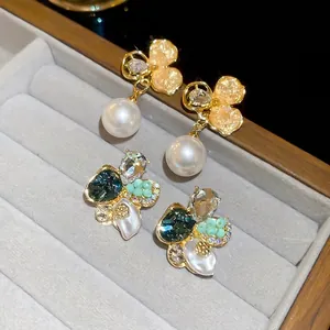 Boucles d'oreilles fleur perle dorées et puces en pierres vertes sur plateau velours