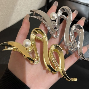 Elegant gold and silver metallic shark hair clips with pearls shown in hand