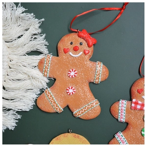 Detail of gingerbread man Christmas ornament with gold glitter and red ribbon on green background