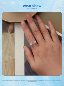 Detail of adjustable silver open ring featuring a white pearl and purple flower design