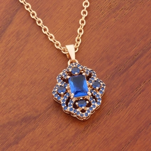 Elegant gold necklace with rectangular blue zircon pendant on a natural wood surface