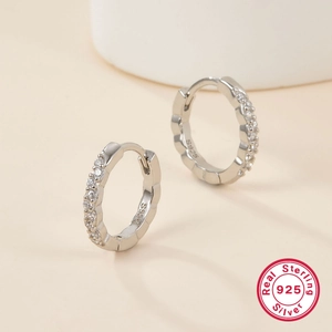 Macro detail of S925 sterling silver hoop earrings with shimmering crystal accents