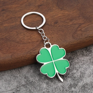 Silver keychain with green enamel four-leaf clover charm on dark wood and stone background