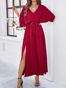 Detail of red V-neck maxi dress featuring elegant waist tie and high side slit