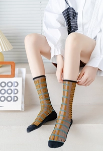 Close-up of sheer mesh socks with vibrant yellow polka dots and blue grid patterns