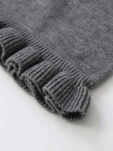 Detailed macro view of gray ribbed knit sweater fabric with delicate ruffle hem edges