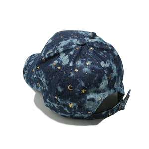 Detail of blue denim baseball cap with gold star and moon prints and metal buckle