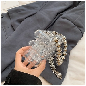 Macro detail of clear acrylic evening bag with silver beaded handle and metal chain