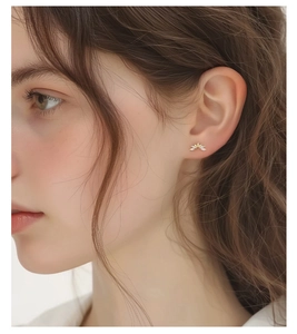 Detail shot of a minimalist gold s925 silver earring with cubic zirconia on female ear