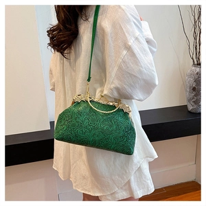 Detail view of green shell bag with embossed floral texture and gold metal frame