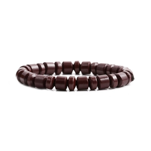 Dettaglio di perle cilindriche rosse e dischi piatti su un bracciale retrò minimalista