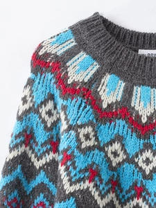 Detail of grey Fair Isle knit sweater showing vibrant blue and red geometric collar patterns