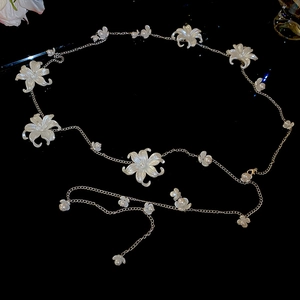 Detailed macro view of white acrylic flowers and pearls on a silver metal waist chain belt