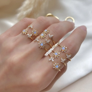 Detail of hand model wearing gold butterfly and flower rings with cubic zirconia stones