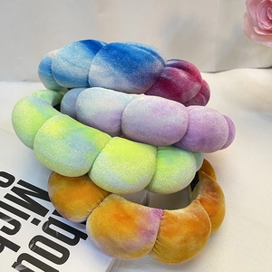 Three tie-dye velvet padded headbands in blue, yellow and orange on a white cloth background