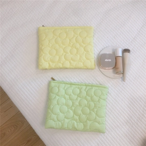 Detailed macro view of quilted floral stitching on soft yellow and green puffer pouch bags