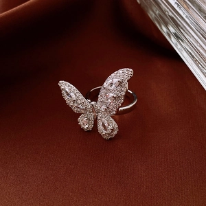 Detailed macro view of a silver butterfly ring with sparkling zircon stones on satin fabric