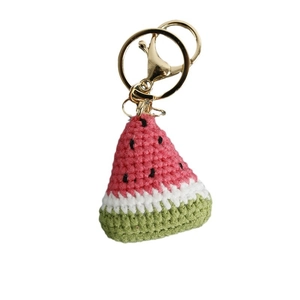 Handmade crochet watermelon keychain with green and red yarn and golden metal clip
