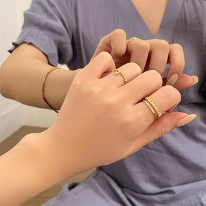 Elegant gold layered rings and bracelet set worn on hand with mirror reflection