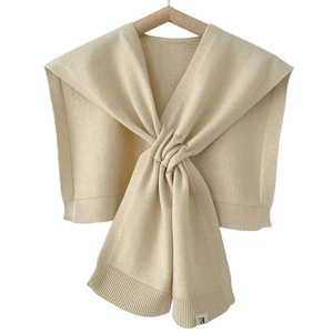Beige knitted shawl wrap for women with elegant twist front design on a wooden hanger