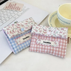 Close-up of floral and plaid fabric pouches with snap buttons on an office desk