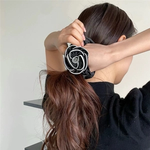 Elegant black and white satin camellia flower scrunchie on woman's ponytail