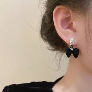Gros plan d'un mannequin portant des boucles d'oreilles nœud velours noir et or
