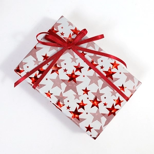 Holiday gift box wrapped in white paper with red stars and a glittering red festive ribbon
