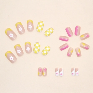 Short square press-on nails with yellow floral patterns and white checkered designs
