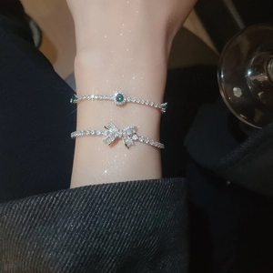 Close-up of zircon bow and green gemstone bracelets set on wrist in focused lighting