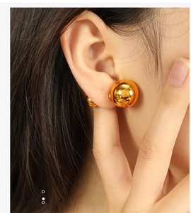 Close-up of minimalist golden spherical double-bead earrings with a polished mirror finish