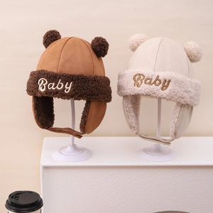 Detail of baby pilot hats in brown and cream with fluffy pom-poms and warm faux fur lining