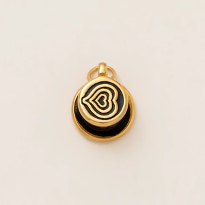 Macro view of golden stainless steel round pendant featuring a black concentric heart design