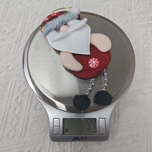 Detailaufnahme des Weihnachtsmann-Plüschstoffs beim Wiegen auf einer Digitalwaage
