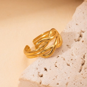 Detailed close-up of a gold-plated titanium woven ring on a beige stone surface