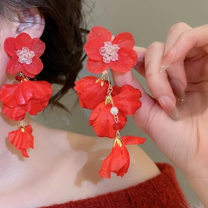 Detailed view of red layered fabric flower earrings with tassel pearls on a model