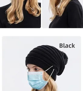 Détail du bonnet en tricot noir avec boutons pour masque et pompon en fausse fourrure