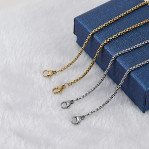 Set of four gold and silver stainless steel box chain necklaces on a soft white background